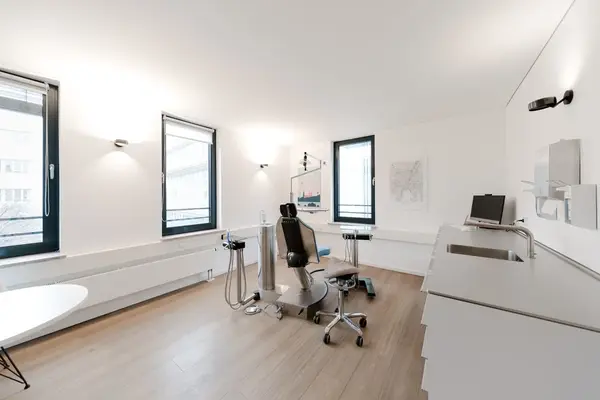 Helles, modernes Behandlungszimmer in einer Zahnarztpraxis mit Behandlungsstuhl und PC.