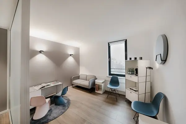 Modern eingerichtetes Wartezimmer mit Designerstühlen, Couch und Tageslichtfenster.