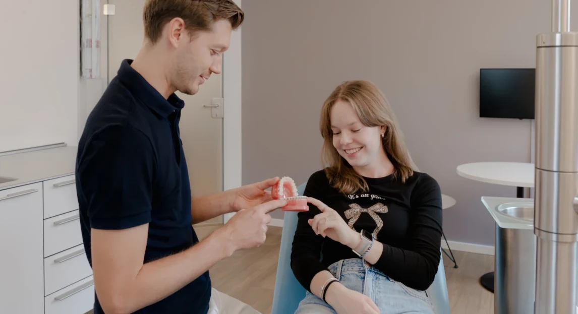 Zahnarzt erklärt Patientin mit Zahnmodell die richtige Zahnpflege in moderner Praxis.